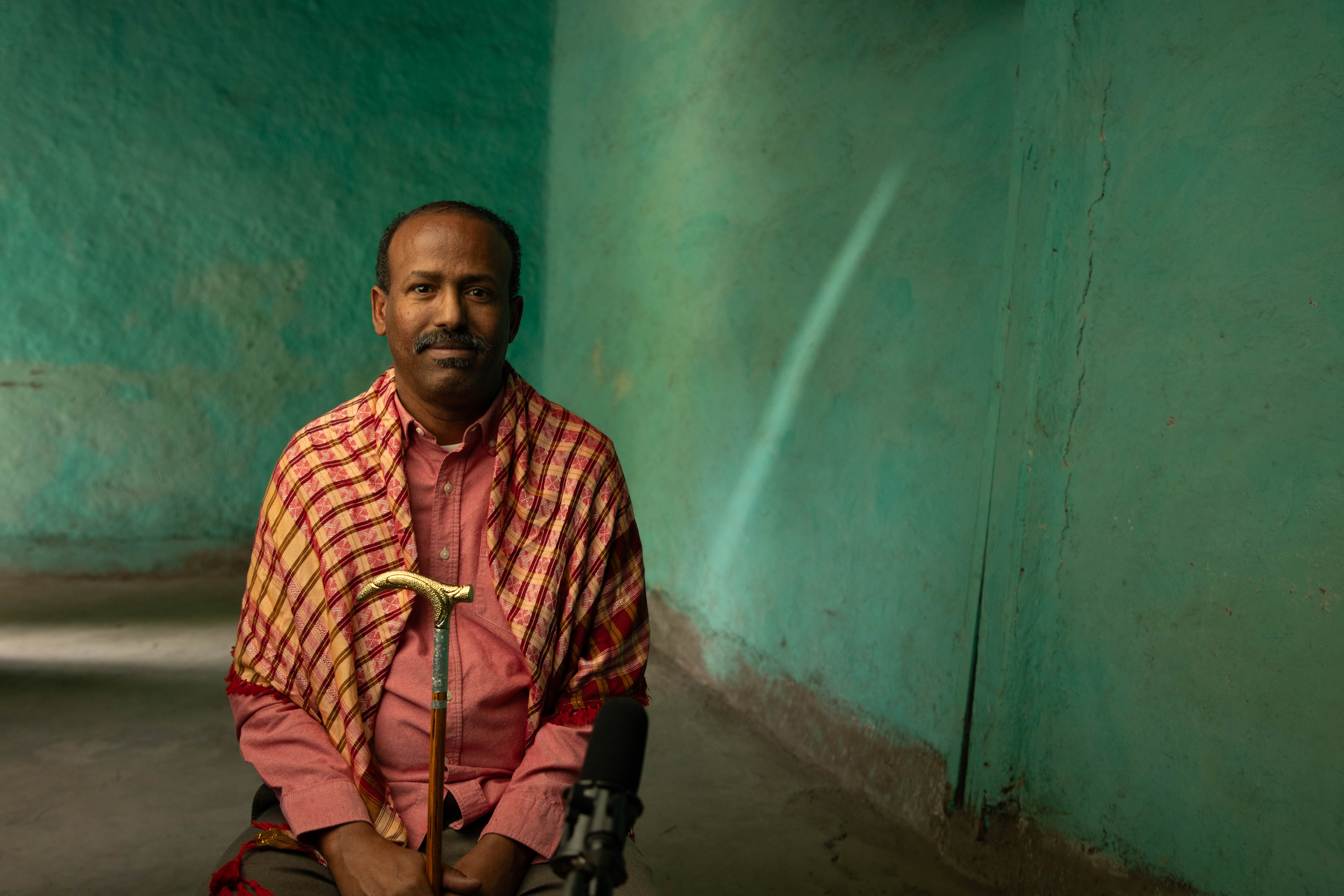 Aweis wearing his shawl holding his cane
