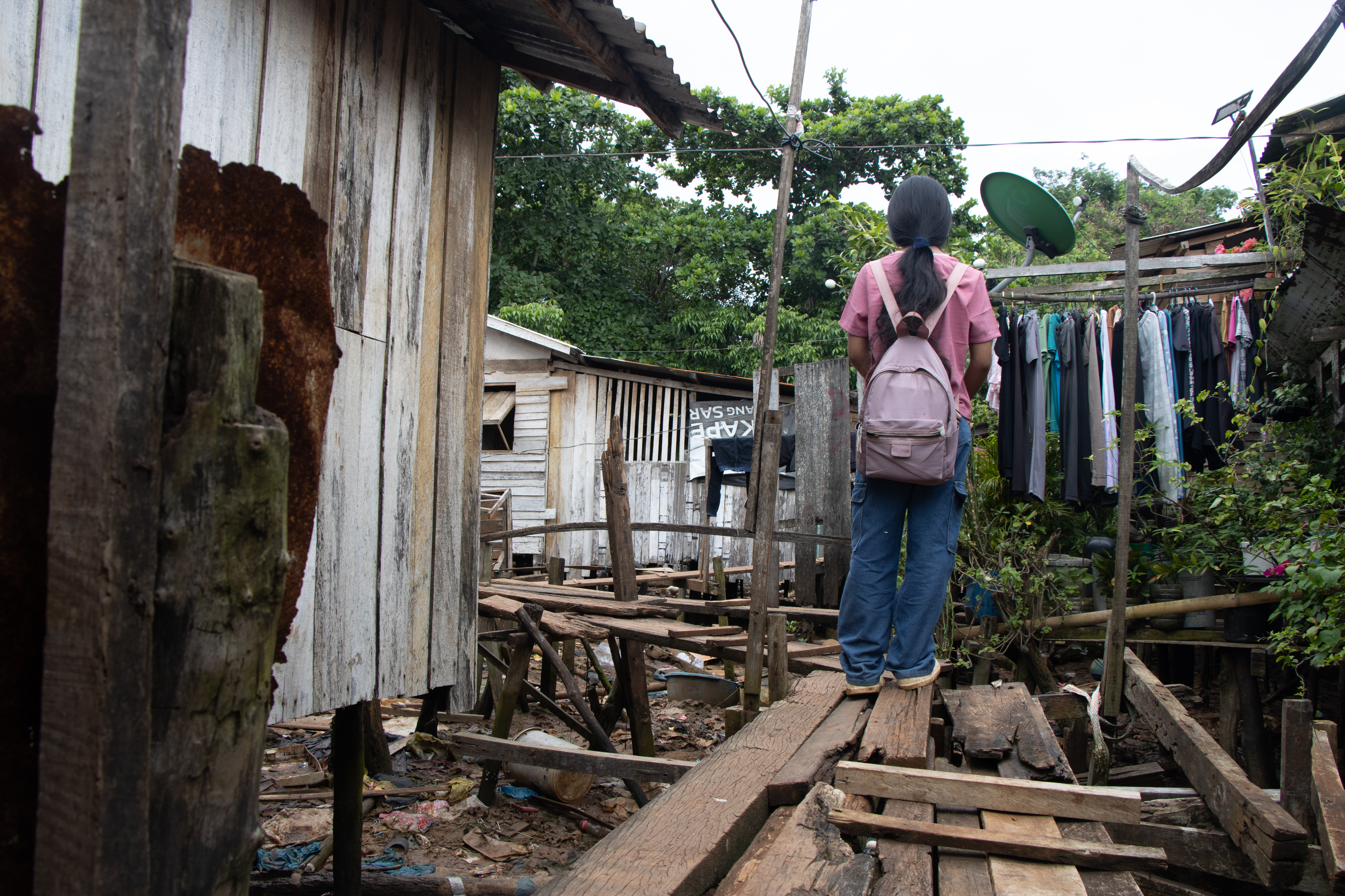 Dayang walking through a narrow stilt pathway to school