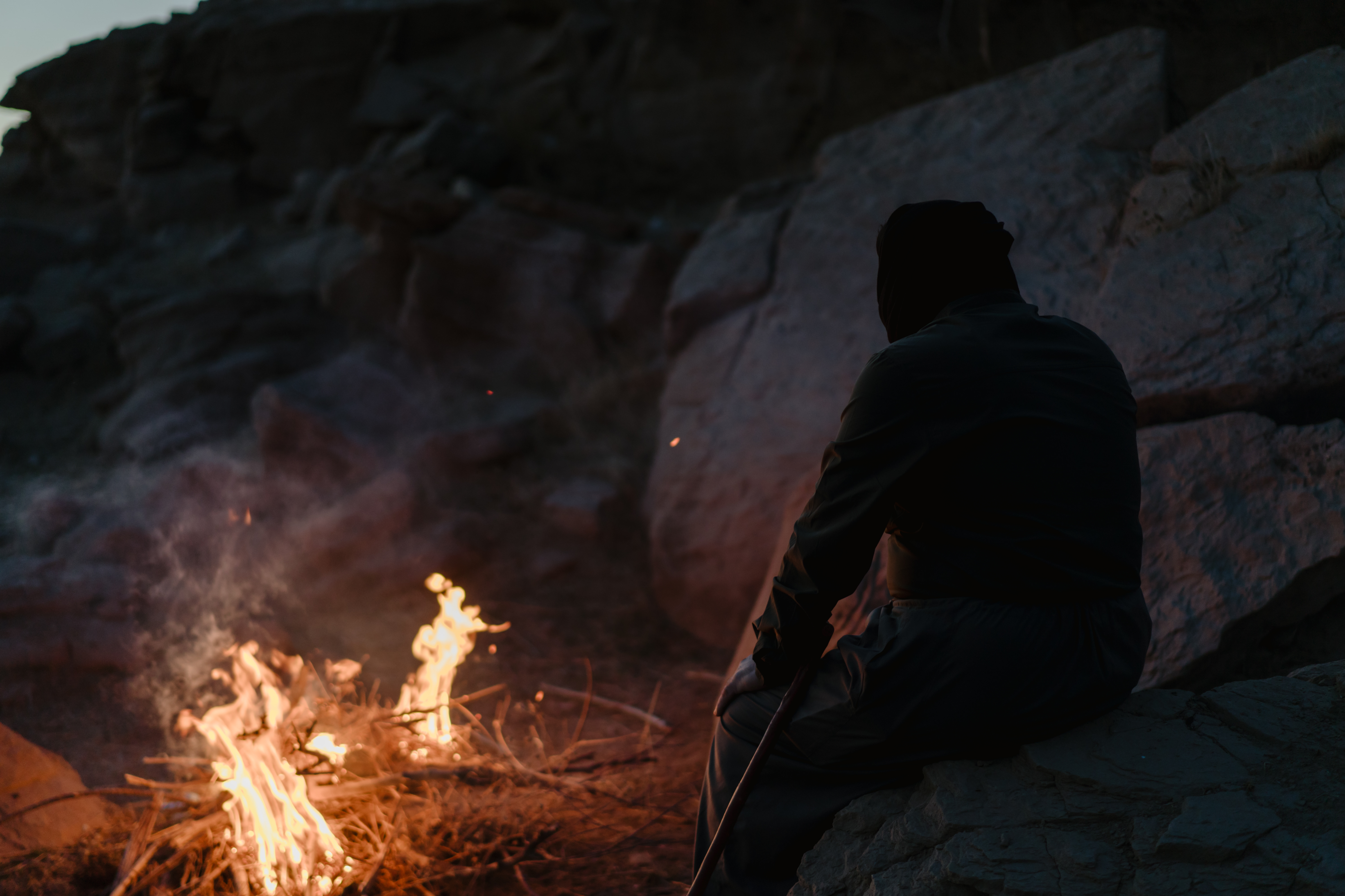 Yasin sitting by a campfire at twilight